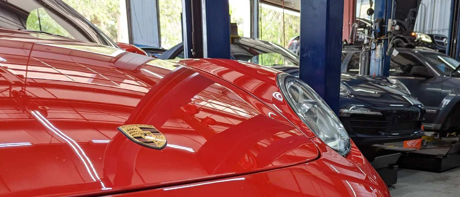 A red Porsche 911 in the shop at Lonnie's Automotive, with cars up on the lifts behind it.
